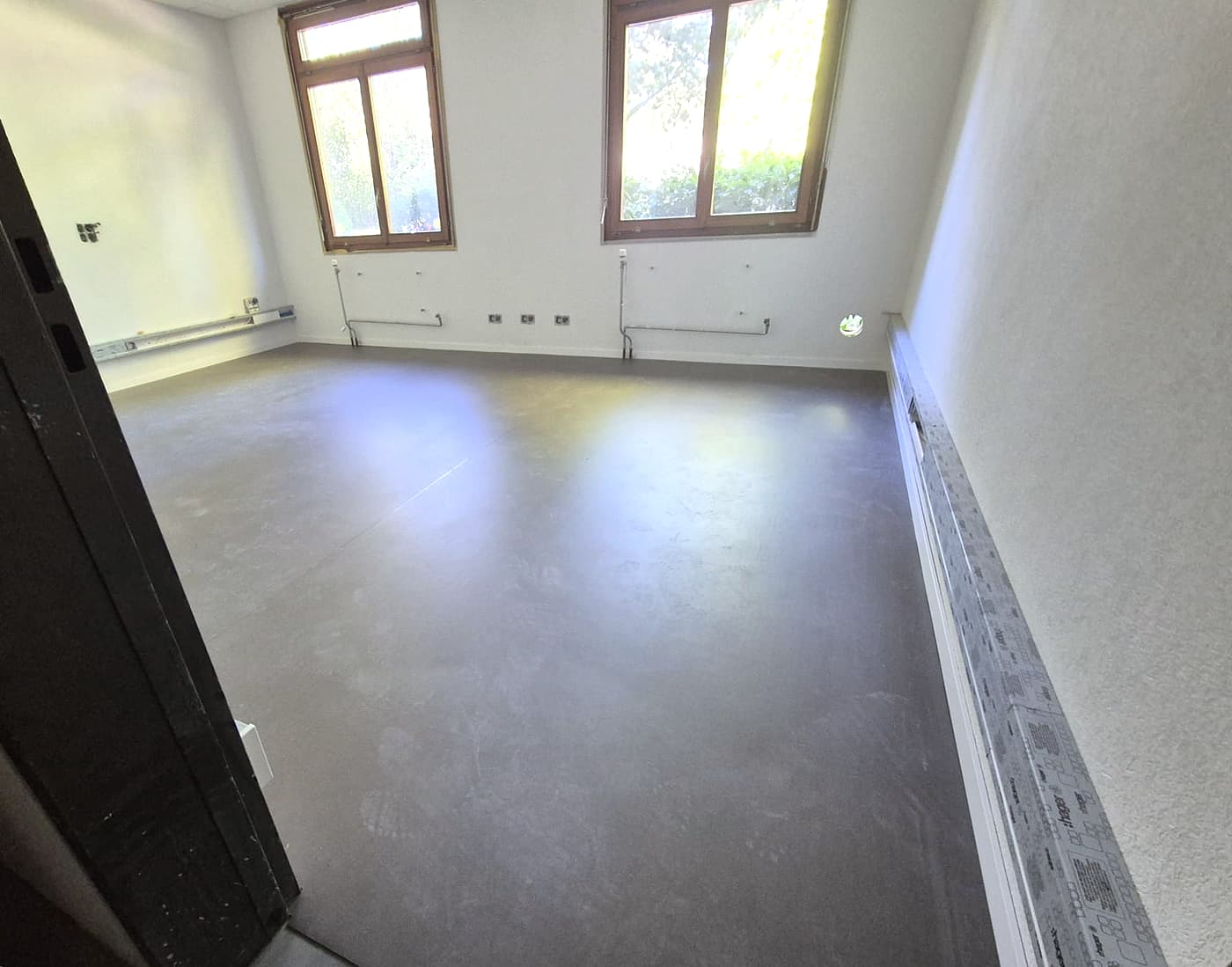 Bureau en linoléum gris, vu depuis la porte, fenêtres au fond