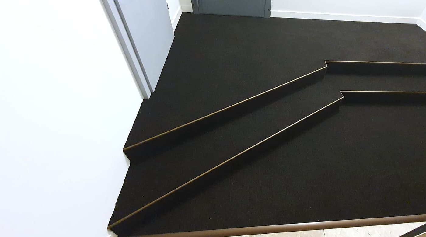 Estrade à gradins revêtue de moquette noire, avec profilés de nez de marche