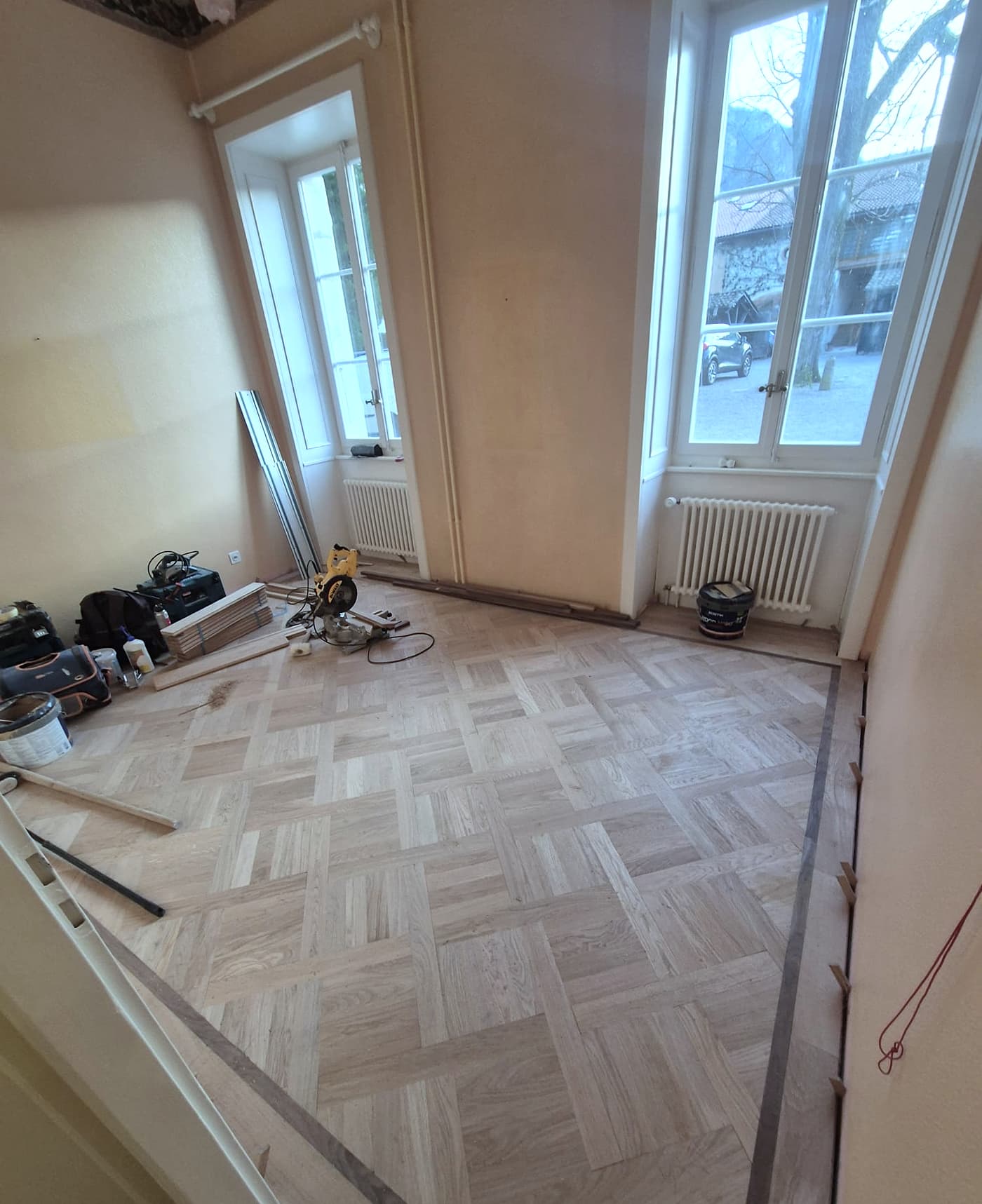Pose des panneaux Versailles en cours, outils et scie sur le chantier