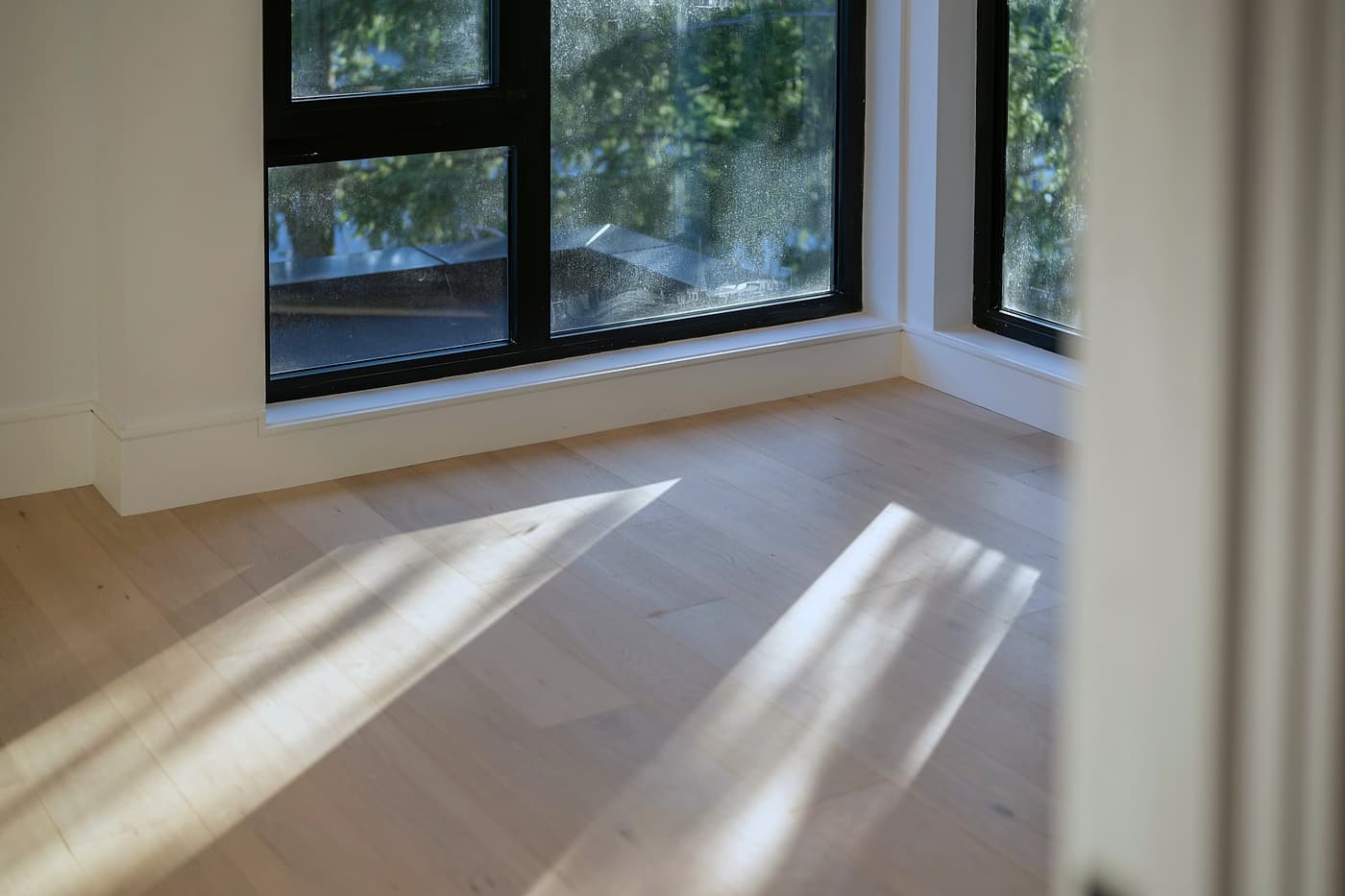 Lumière du jour traversant une pièce et glissant sur un plancher en bois clair